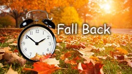 Fall Back. Alarm clock sitting in a pile of leaves.
